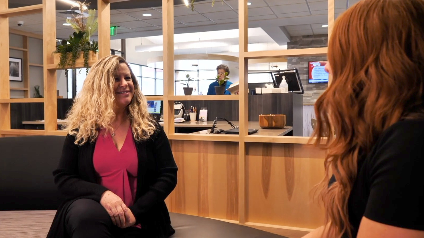 leave-us-a-review Two smiling women sitting in a modern bank lobby