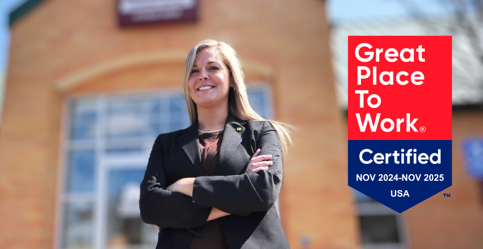 A confident woman standing in front of a Sturgis Bank branch smiling with her arms crossed